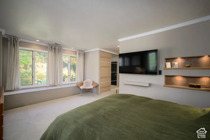 Recessed lighting, built-in shelving with integrated illumination, wall-mounted television, and expansive windows