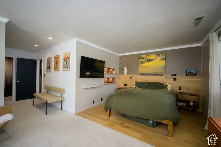 Recessed lighting, crown molding, light wood-finish flooring, built-in wooden headboard, and integrated wall shelving