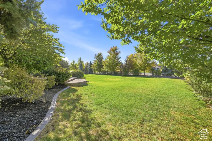 Expansive lawn area with mature trees and established landscaping featuring a stone-edged garden bed