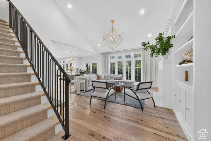 Hardwood flooring, vaulted ceiling, built-in shelving, large window array, and a geometric chandelier