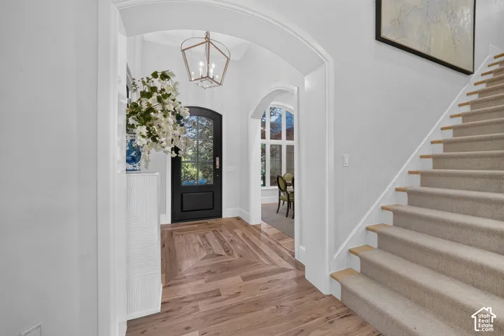 Arched entryway with a dark wood door, herringbone wood-finish flooring, and a bronze-finish ceiling lantern