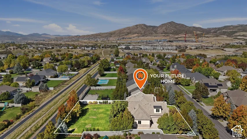 Expansive property featuring a large green space, mature trees, mountain backdrop, and surrounding residential structures