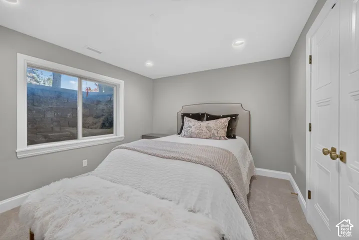 Recessed lighting, wall-to-wall carpeting, and a window with white trim
