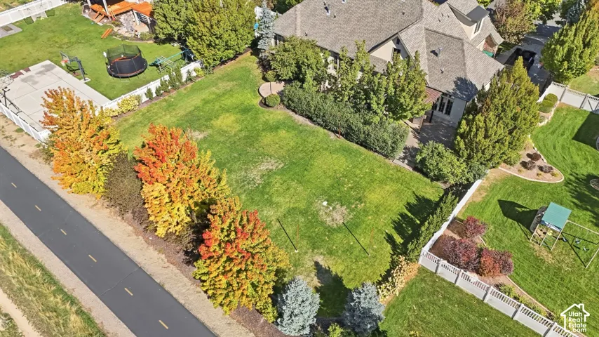 Expansive green lawn surrounded by mature trees, privacy hedges, and a white fence