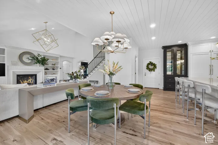 Open-concept living area with wood-finish flooring, a contemporary fireplace, built-in shelving, and a vaulted shiplap ceiling
