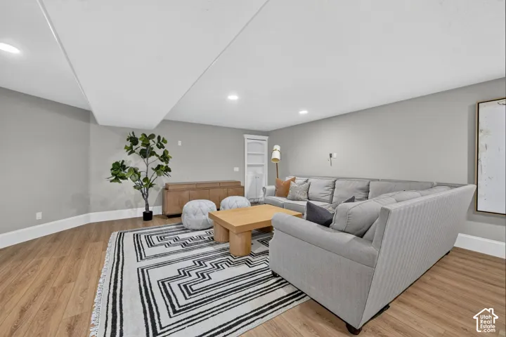 Recessed ceiling lighting, wood-finish flooring, light gray wall tones, and white trim