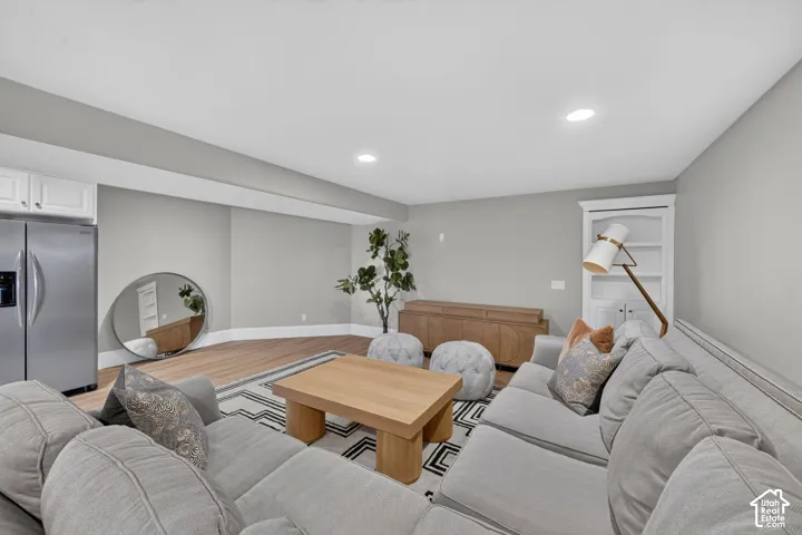 Recessed lighting, wood-finish flooring, built-in white cabinetry, stainless steel refrigerator, and built-in white shelving