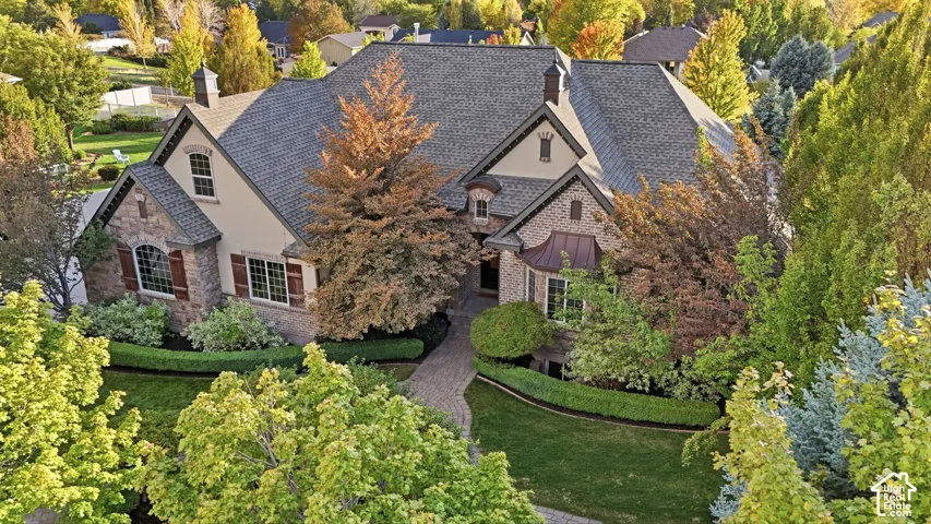 Stately residence featuring a stone and stucco exterior, dark shingle roof, and multiple gables