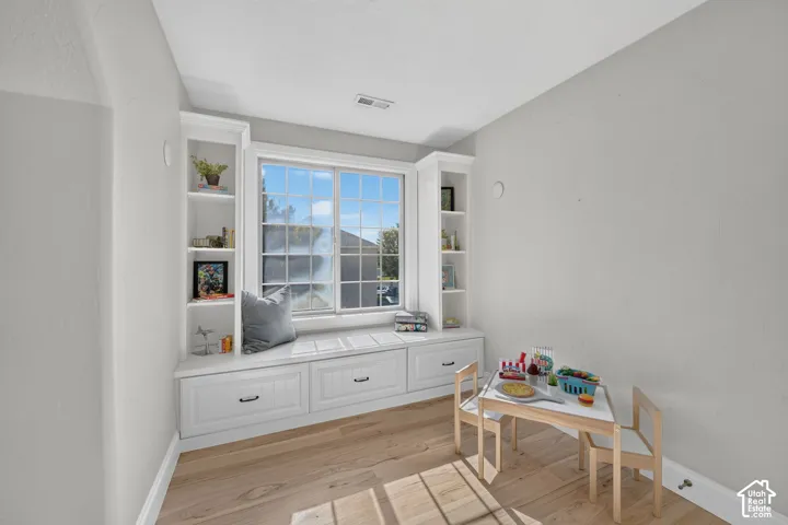 Built-in window seat with storage drawers, integrated shelving, and wood-finish flooring