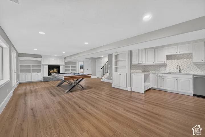 Expansive open-concept room featuring wood-finish flooring, recessed lighting, and a built-in fireplace with a stone surround