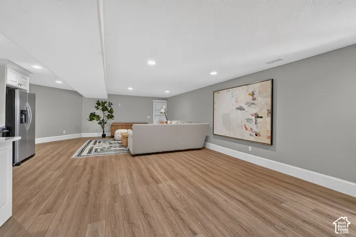 Spacious room featuring wood-finish flooring and recessed lighting
