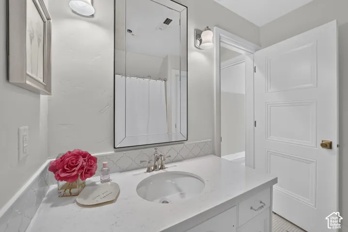 White vanity with a single basin, chrome faucet, and quartz countertop