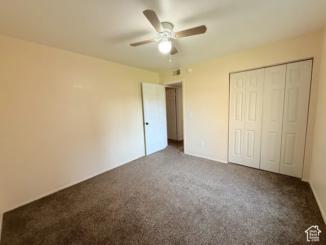 Textured carpeting, neutral wall finishes, ceiling fan with integrated lighting, paneled doors, and a bi-fold closet