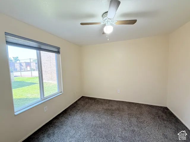 Neutral-toned walls, gray textured carpeting, and a ceiling fan with integrated lighting