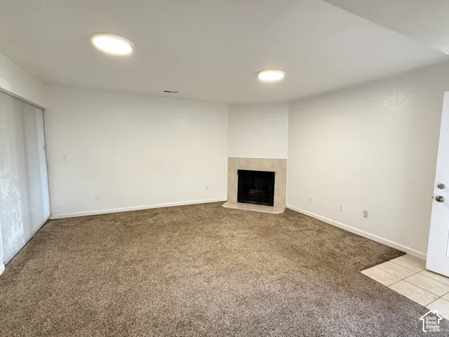 Fireplace with tiled surround, recessed ceiling lighting, carpeted flooring, and tiled entry