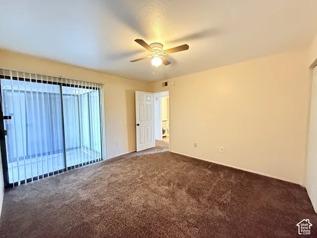 Sliding glass door, textured brown carpeting, ceiling fan with light fixture, and paneled interior door