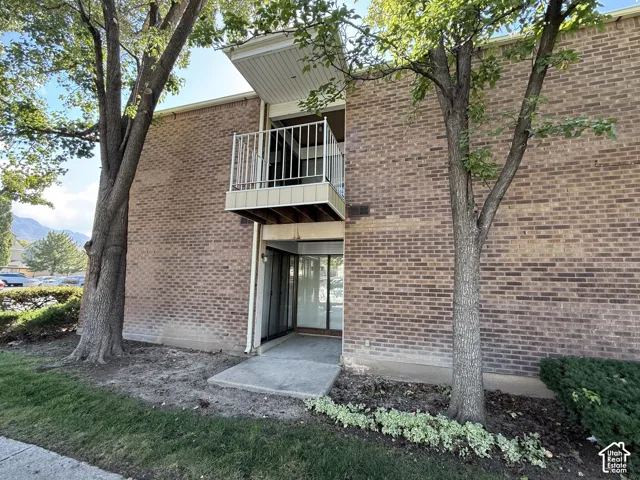 Brick exterior with an upper-level balcony featuring metal railings and a wood-finish soffit