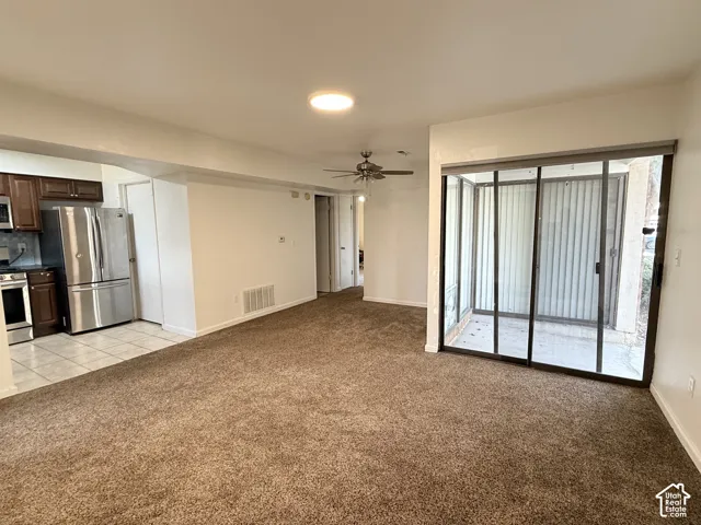 Open-concept living space with plush carpeting, a ceiling fan, and a light fixture