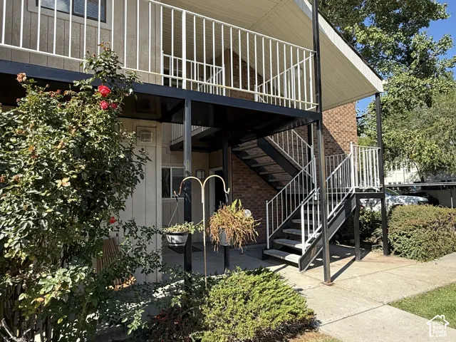 Metal exterior staircase with white railings, brick facade, and landscaping with mature shrubs