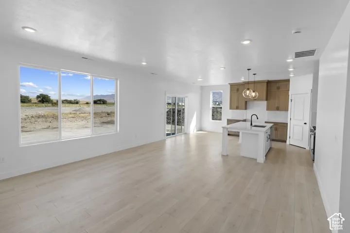 Expansive open-concept space featuring light wood-finish flooring, recessed lighting, and a large multi-pane window