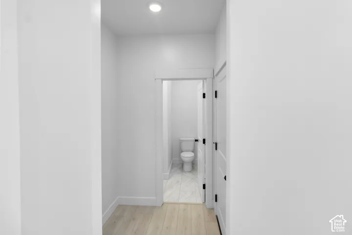 Recessed ceiling light, white interior doors with matte black hardware, wood-finish flooring, white walls, and white trim
