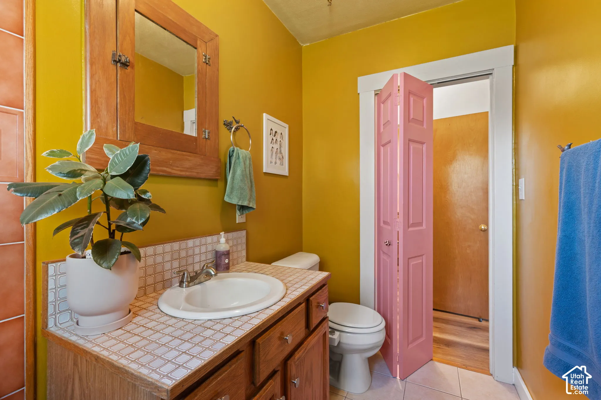 Vanity with a drop-in sink, tiled countertop, and wood-finish cabinetry