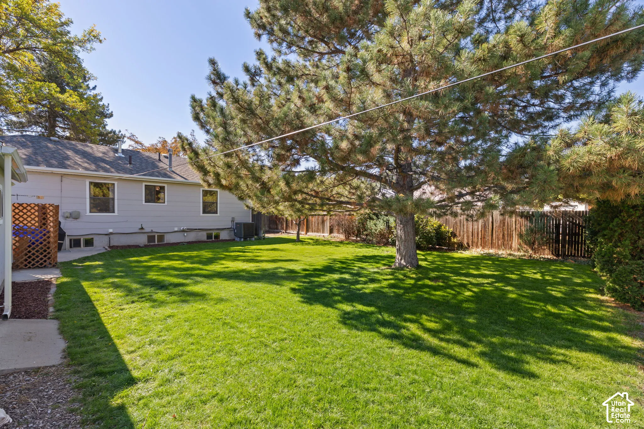 Expansive lawn featuring mature trees and a fenced perimeter