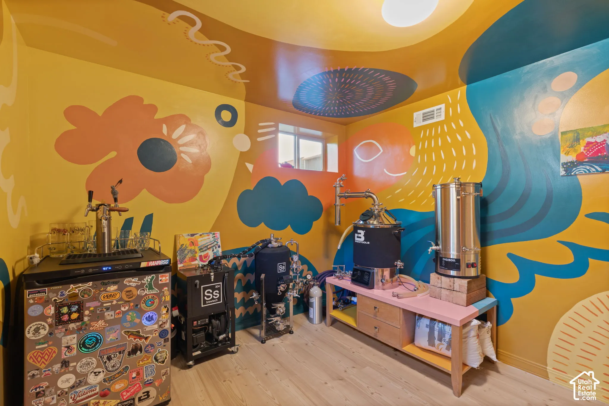 Dedicated utility room with artistic wall murals, wood-finish flooring, and built-in window