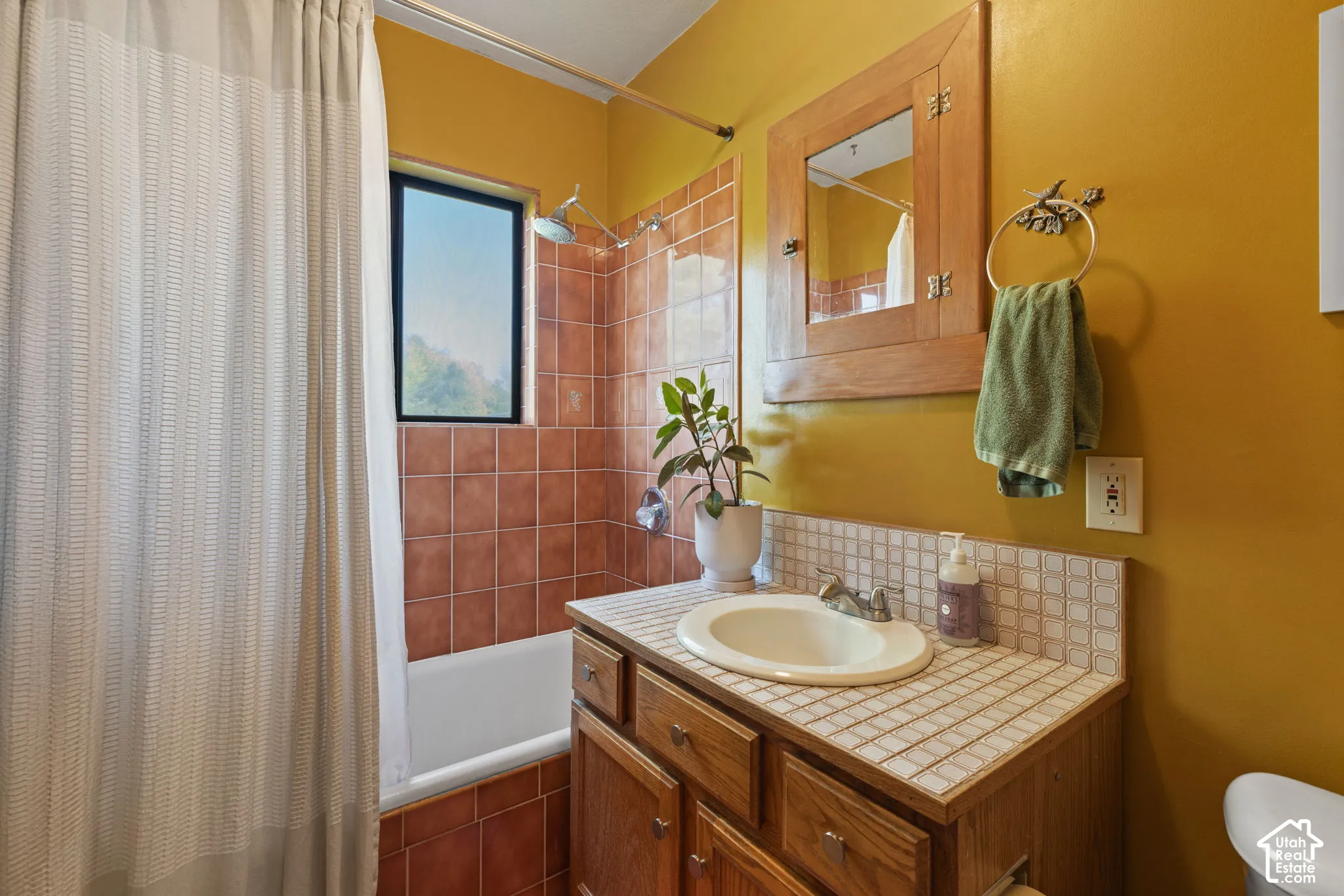 Bathroom featuring a built-in wood vanity with tile countertop, integrated sink, and wood-framed mirror