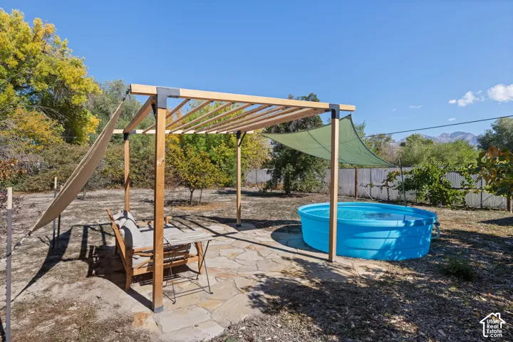 Backyard featuring a wood pergola with shade sails, a freestanding round pool, and a flagstone patio area