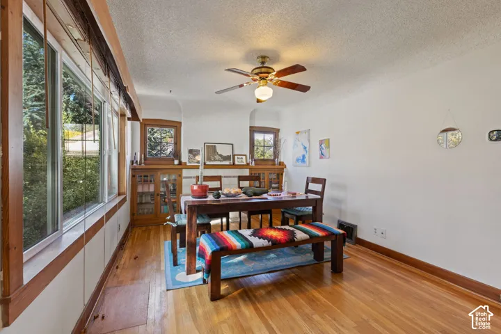 Wood-finish flooring with extensive wood trim accents, built-in cabinetry, and a ceiling fan with integrated lighting