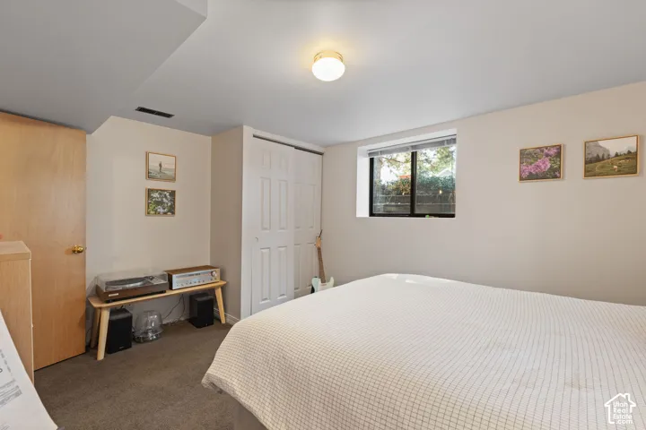 Carpeted flooring, egress window, white bi-fold closet doors, and wood-finish interior door