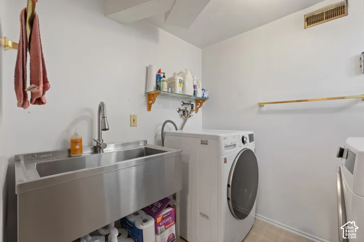 Utility room featuring a stainless steel sink, a pull-down faucet, and a wall-mounted glass shelf