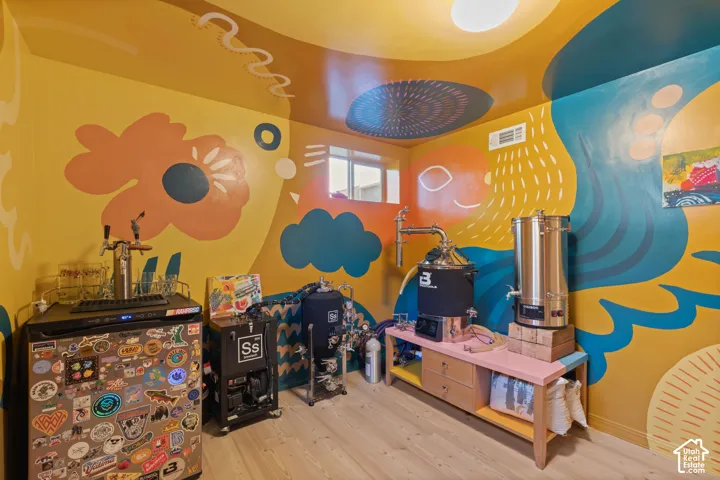 Dedicated utility room with artistic wall murals, wood-finish flooring, and built-in window