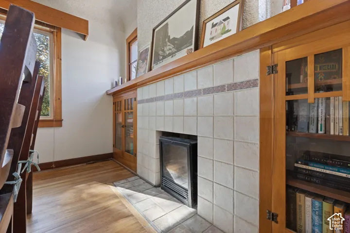 Built-in fireplace with a tiled surround, wood-finish flooring, and built-in cabinetry with glass paneling