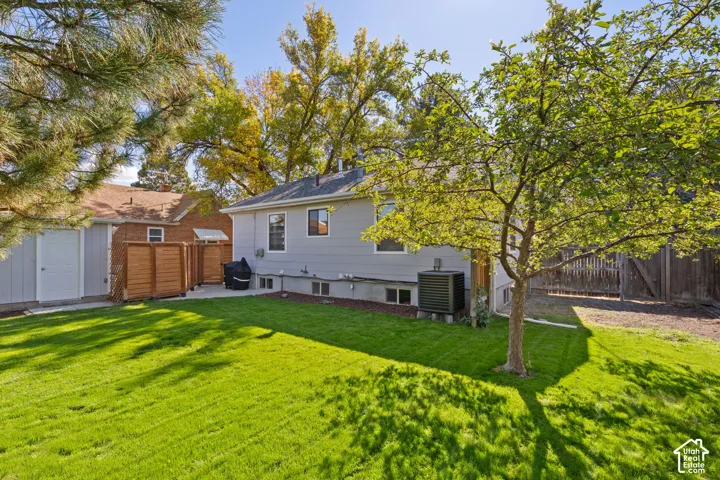 Expansive green lawn, mature trees, and a private patio area featuring wood privacy screens