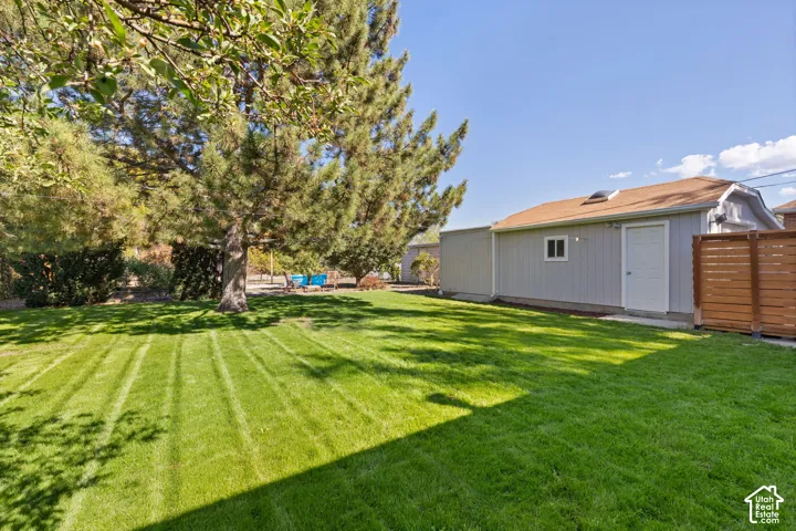 Expansive backyard featuring a manicured lawn, mature trees, and a privacy fence