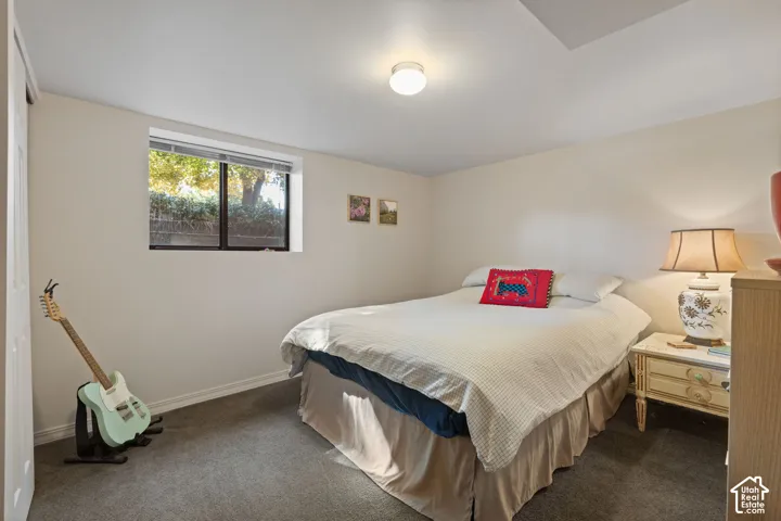 Recessed window with exterior greenery, neutral wall color, built-in closet with bi-fold door, carpeted flooring, and flush-mount ceiling light