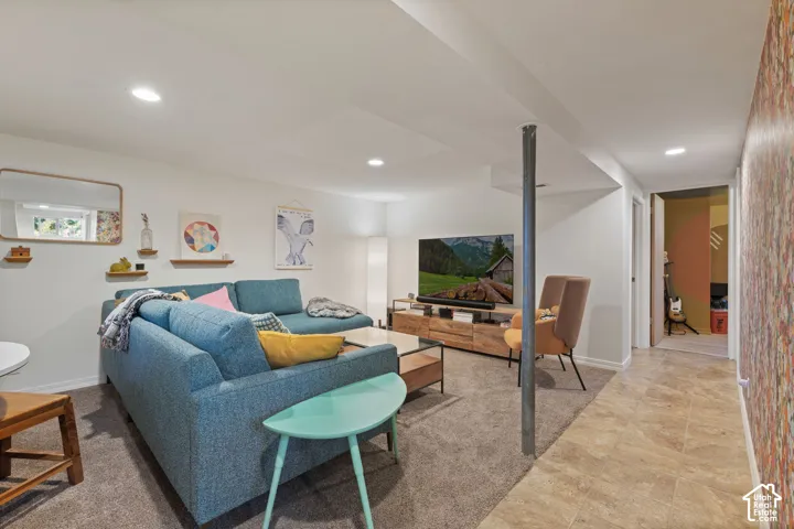 Recessed lighting, wood-finish media console, neutral wall color, tiled flooring, and carpeted area