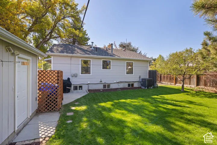 Expansive lawn area with mature trees, concrete patio, and a dedicated storage shed