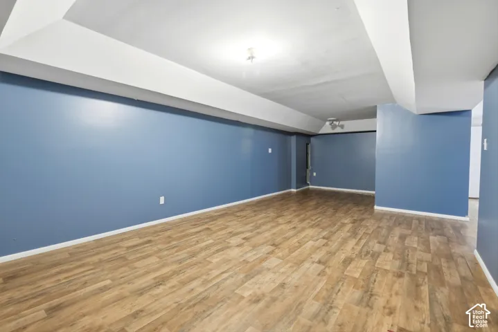 Spacious room featuring wood-finish flooring, blue-painted walls, and white ceiling trim