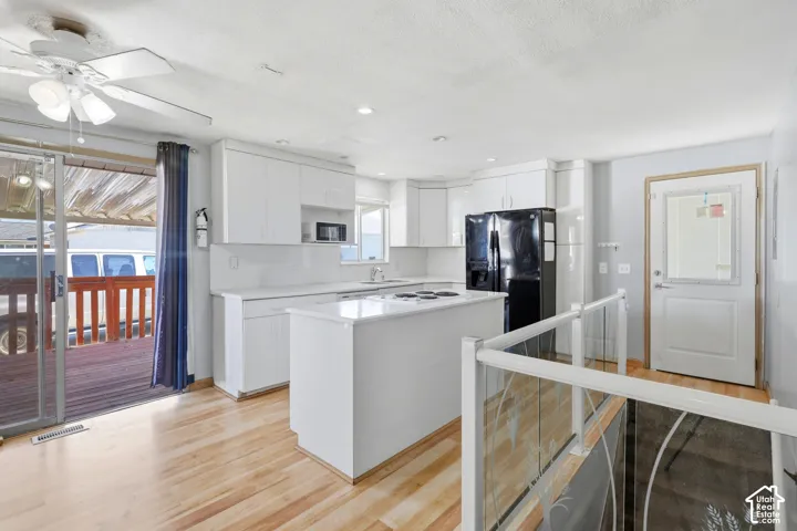 Kitchen featuring white cabinetry, a central island with cooktop, and wood-finish flooring