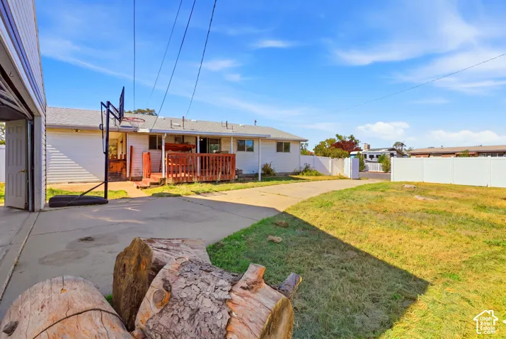 Spacious outdoor area featuring a concrete driveway, a rear wood deck, and a fenced perimeter