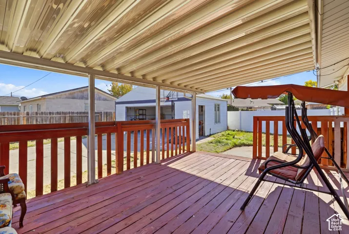 Covered outdoor deck with red-stained wood flooring and matching railings