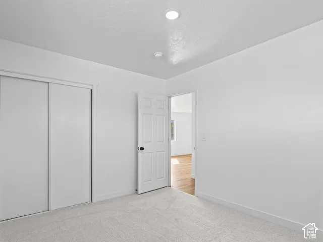 Plush carpet flooring with white walls, a white sliding closet door, and a white interior door with black hardware