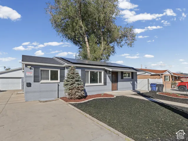 Single-story dwelling with a detached garage, solar panel installation, and a dark asphalt shingle roof