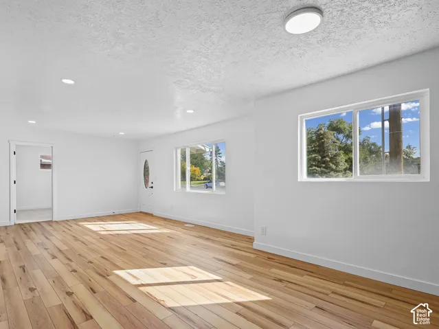 Hardwood flooring, recessed lighting, white walls, multiple windows, and a glass-paneled entry door