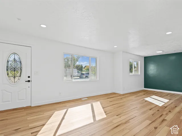 Hardwood flooring, recessed lighting, white walls, and a decorative front door with leaded glass