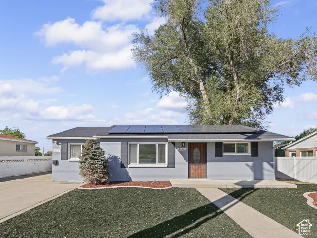 Single-story residence featuring a gray exterior, black shutters, and solar panels
