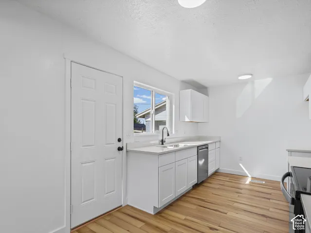 Kitchen featuring white cabinetry, light countertops, wood-finish flooring, and stainless steel appliances